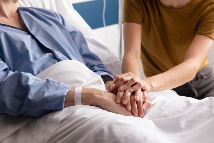 Two people holding hands at a hospital bed, symbolizing the moment they realized they had fallen out of love.
