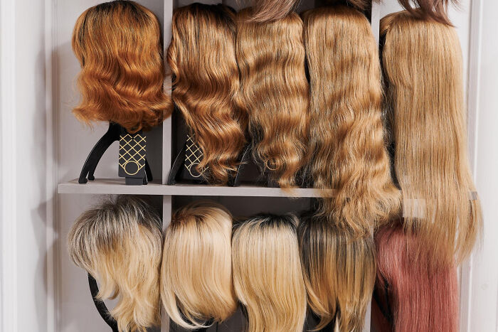 Assorted hair extensions of various colors and textures displayed on shelves in a beauty supply setting.