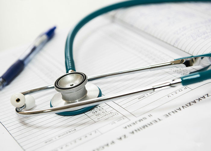 Stethoscope and pen on medical documents highlighting common purchases people have ditched due to ridiculous price tags.