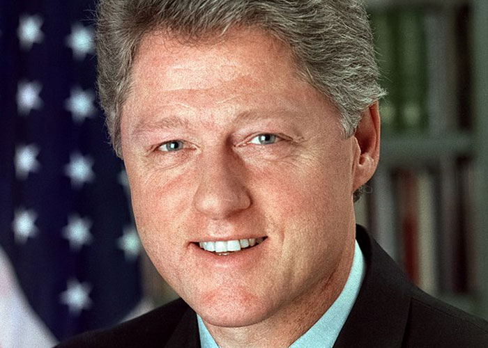 Close-up of a man in a suit with an American flag in the background representing historical events impacting society.