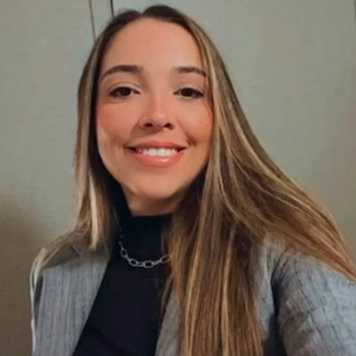 Smiling woman with long hair wearing a gray blazer and black top, related to plastic surgeon arrested after butt lift procedure. Smiling woman with long hair wearing a gray blazer and black top, related to plastic surgeon arrested after butt lift procedure.