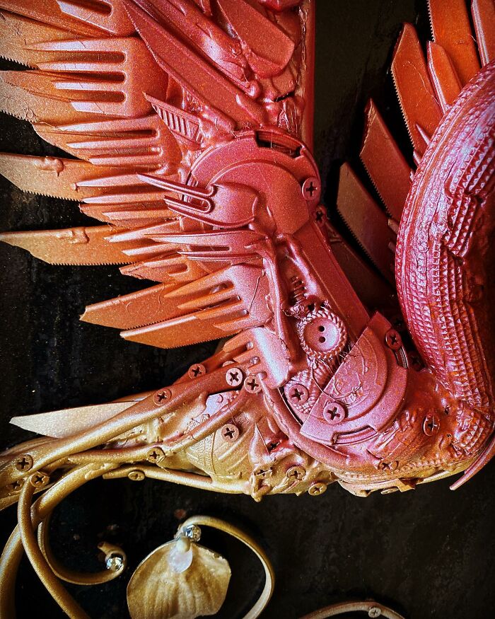 Intricate animal sculpture made from recycled trash, featuring a colorful bird with mechanical wings and curling metal vines.