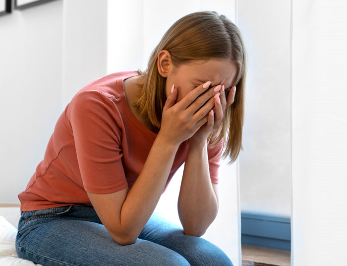 Sad young woman covering her face with hands, stressed and emotional, reflecting single sister can't handle sibling's engagement. Sad young woman covering her face with hands, stressed and emotional, reflecting single sister can't handle sibling's engagement.