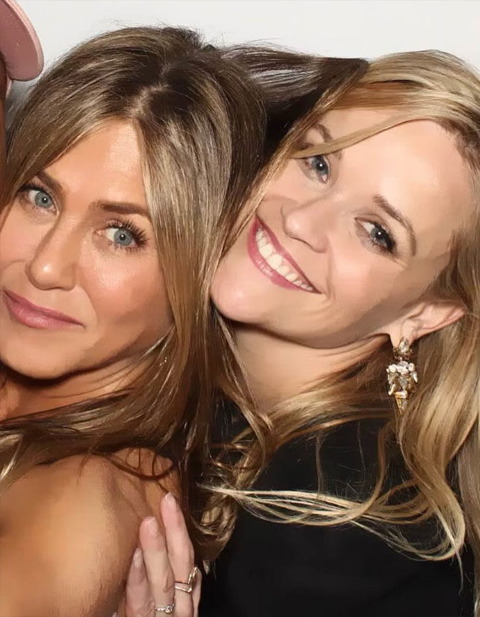 Jennifer Aniston and Reese Witherspoon smiling closely together in a candid, friendly moment. Jennifer Aniston and Reese Witherspoon smiling closely together in a candid, friendly moment.