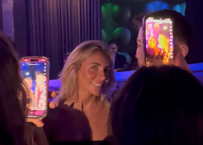 Adult star Bonnie Blue smiling in nightclub crowd with phones capturing the event amid chaos and intense lighting. Adult star Bonnie Blue smiling in nightclub crowd with phones capturing the event amid chaos and intense lighting.