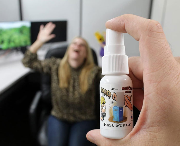 Hand holding a prank fart spray bottle with a blurred woman reacting in a school office, related to teacher using poop spray incident. Hand holding a prank fart spray bottle with a blurred woman reacting in a school office, related to teacher using poop spray incident.
