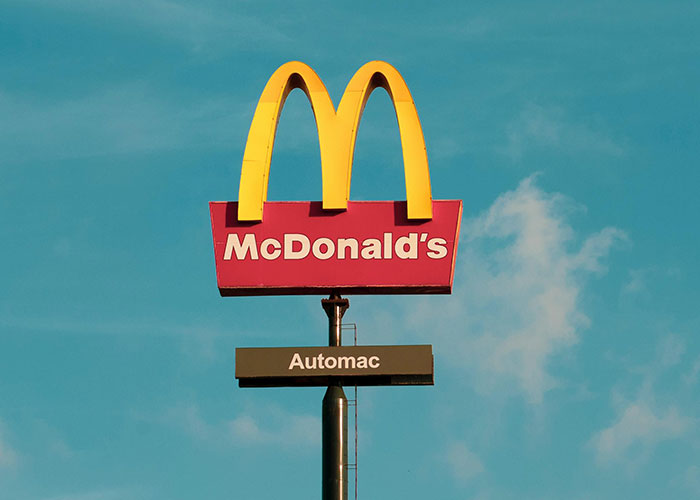 McDonald's sign against blue sky representing common purchases people have ditched due to ridiculous price tags.
