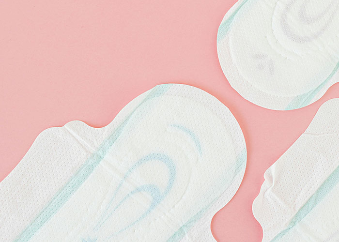 Close-up of feminine hygiene products on pink background representing common purchases ditched due to ridiculous price tags