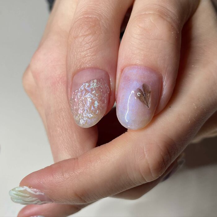 Close-up of unconventional nail designs with textured and iridescent effects showcasing creative nail art techniques.