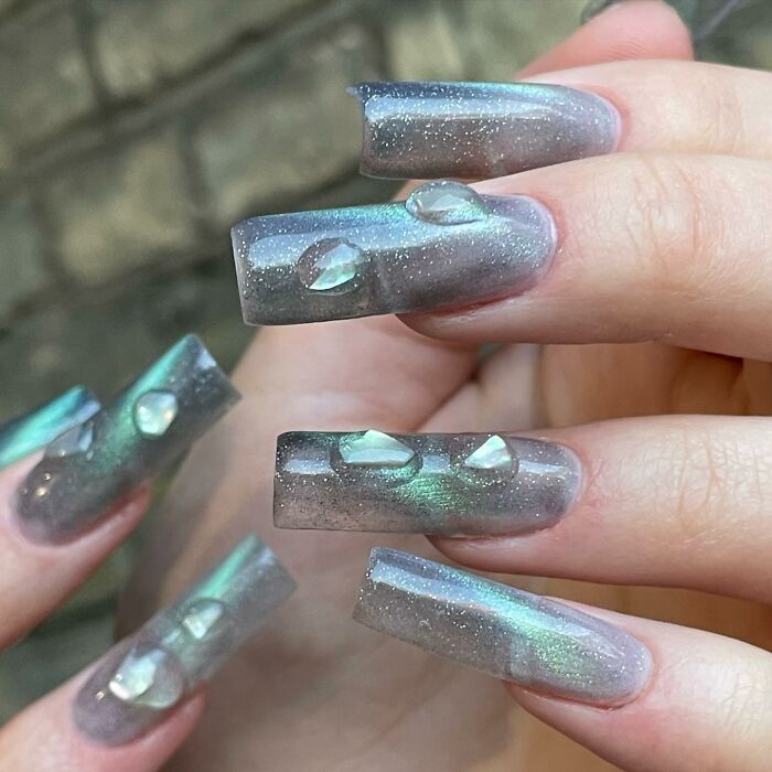 Long acrylic nails with green shimmer and 3D water droplet nail designs showcasing bold nail designs.
