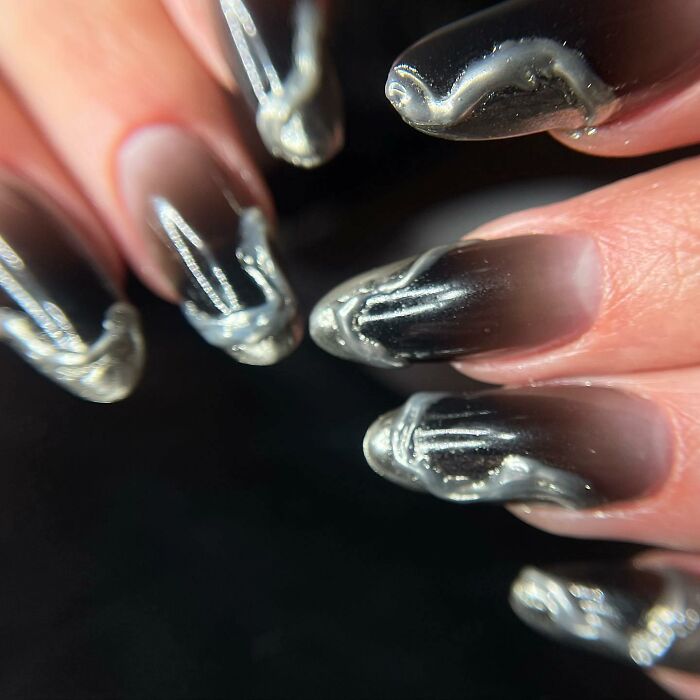 Metallic and black 3D swirl nail designs on long almond-shaped nails showcasing bold nail designs.