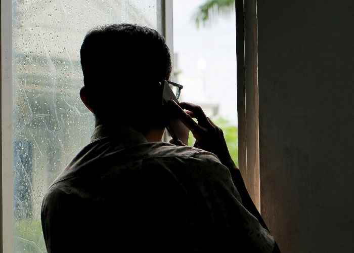 Silhouette of a man making a phone call by a window with rain droplets, conveying a mother poisoned me theme. Silhouette of a man making a phone call by a window with rain droplets, conveying a mother poisoned me theme.