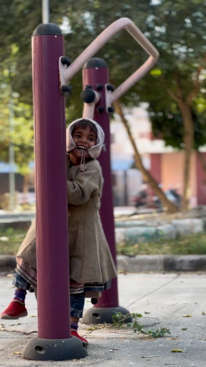 Child smiling and playing outdoors, captured in street photography that highlights humanity in its purest form.