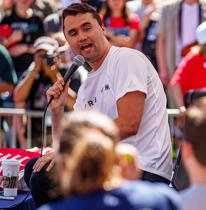 Man speaking into microphone at an outdoor event with crowd, related to The Rock's daughter and Charlie Kirk remarks. Man speaking into microphone at an outdoor event with crowd, related to The Rock's daughter and Charlie Kirk remarks.