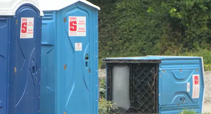 Blue porta-potty units at an outdoor site, one tipped over, related to cop opening fire on teens over prank incident. Blue porta-potty units at an outdoor site, one tipped over, related to cop opening fire on teens over prank incident.