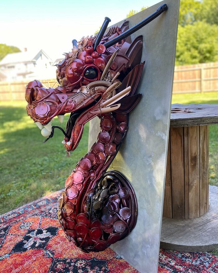 Sculpture of a dragon head made from recycled trash materials, showcasing stunning animal sculptures art outdoors.