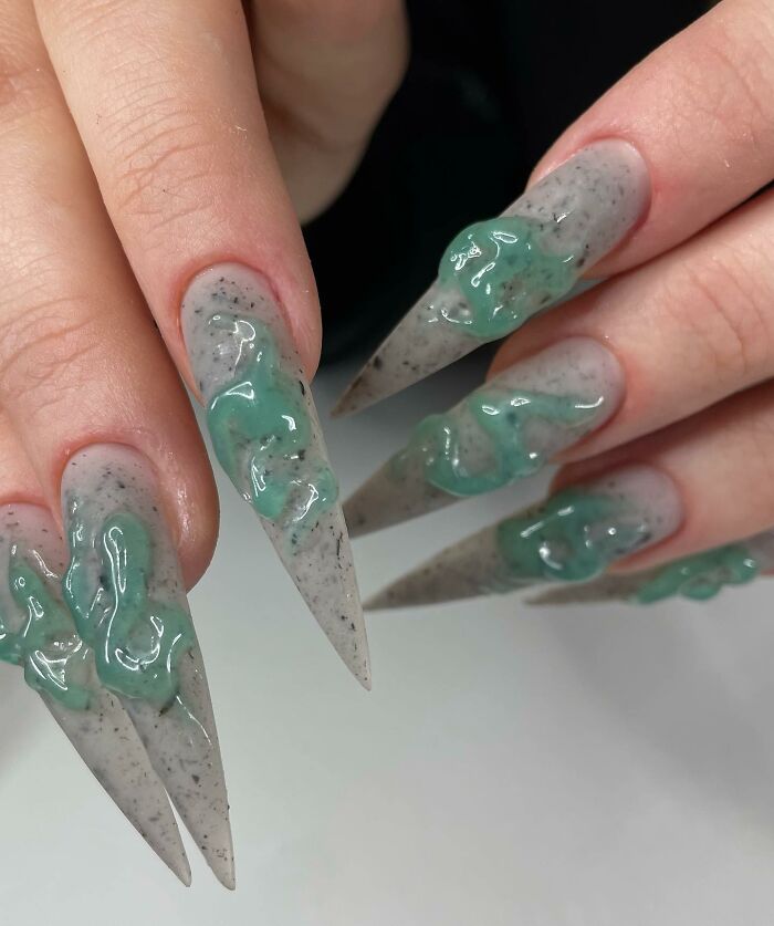 Long pointed nail designs with green 3D gel accents on a gray speckled base, showcasing unique and creative nail art.