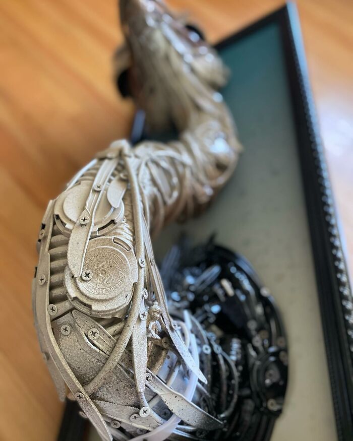 Sculpture of an animal made from trash, featuring intricate details and framed against a blue background.