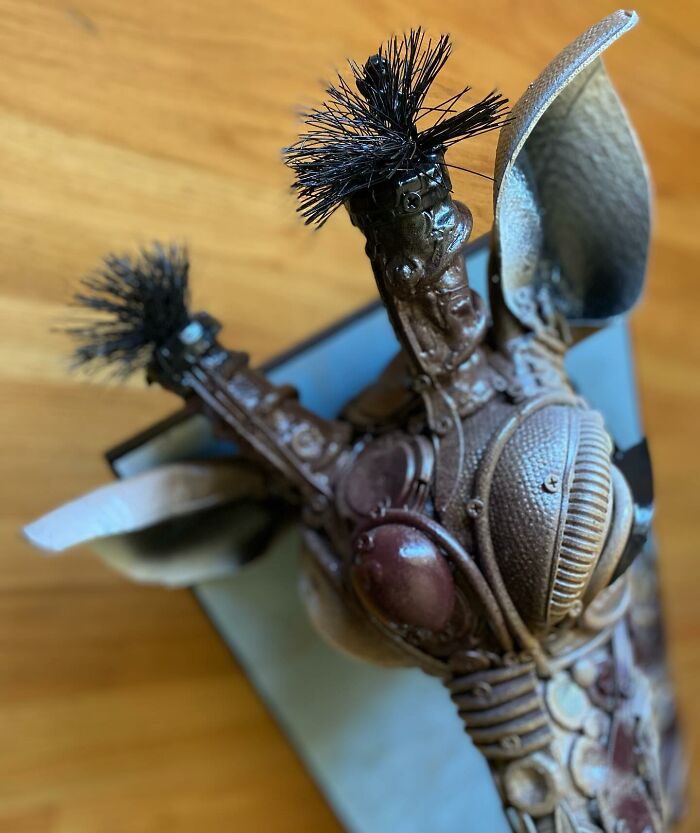Sculpture of a giraffe made from trash, showcasing stunning animal art crafted with recycled materials on a wooden floor.