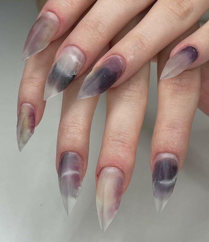 Translucent matte stiletto nail designs with smoky purple and gray accents showcasing bold nail design trends.