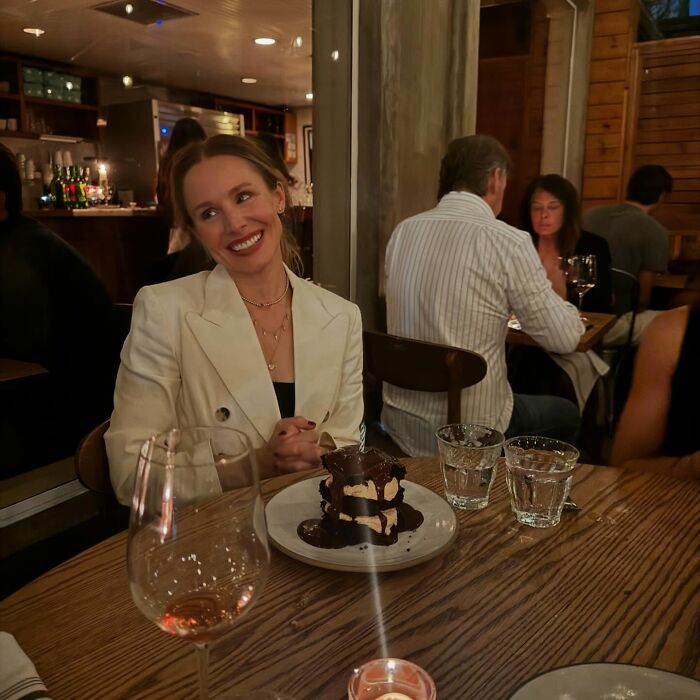 Kristen Bell smiling at a restaurant table with dessert and drinks, showcasing a simple biohacking trick for fitness. Kristen Bell smiling at a restaurant table with dessert and drinks, showcasing a simple biohacking trick for fitness.