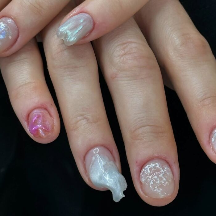 Close-up of unique 3D nail designs with glossy, wavy textures in pink and silver, showcasing creative nail designs.