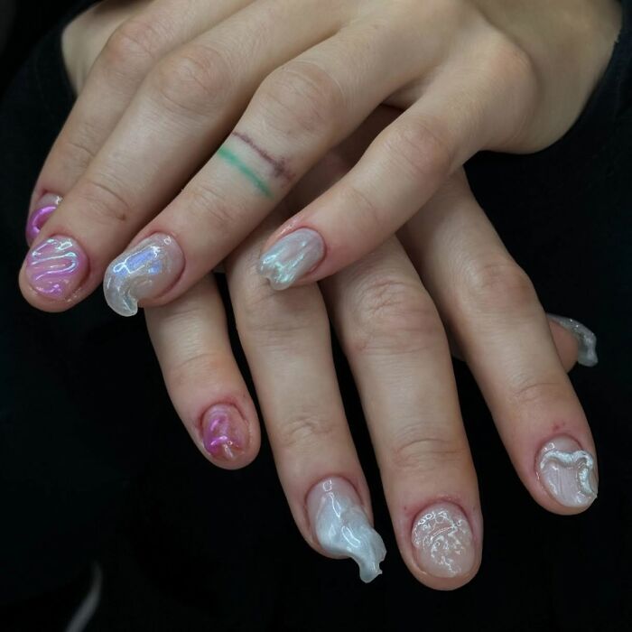Close-up of unique 3D nail designs with glossy, wavy textures in pink and silver, showcasing creative nail designs.