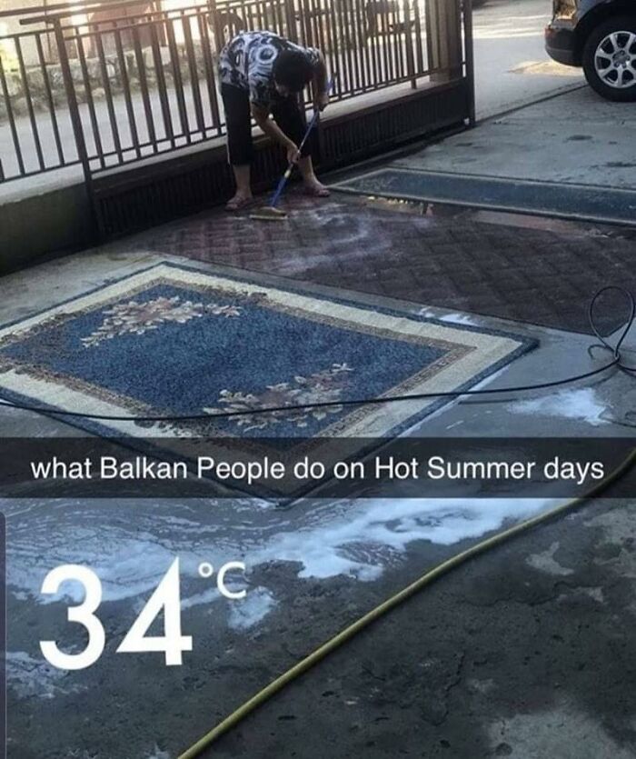 Person cleaning a carpet outdoors with water and a brush on a hot summer day, relatable Eastern Europe meme.