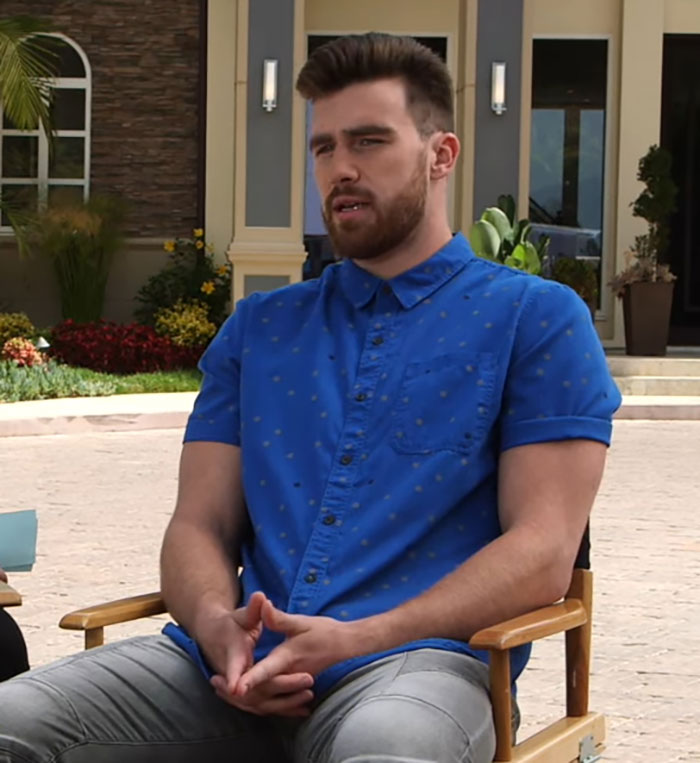 Man in blue shirt sitting outdoors, discussing Travis Kelce’s answer about Taylor Swift in a resurfaced video clip. Man in blue shirt sitting outdoors, discussing Travis Kelce’s answer about Taylor Swift in a resurfaced video clip.
