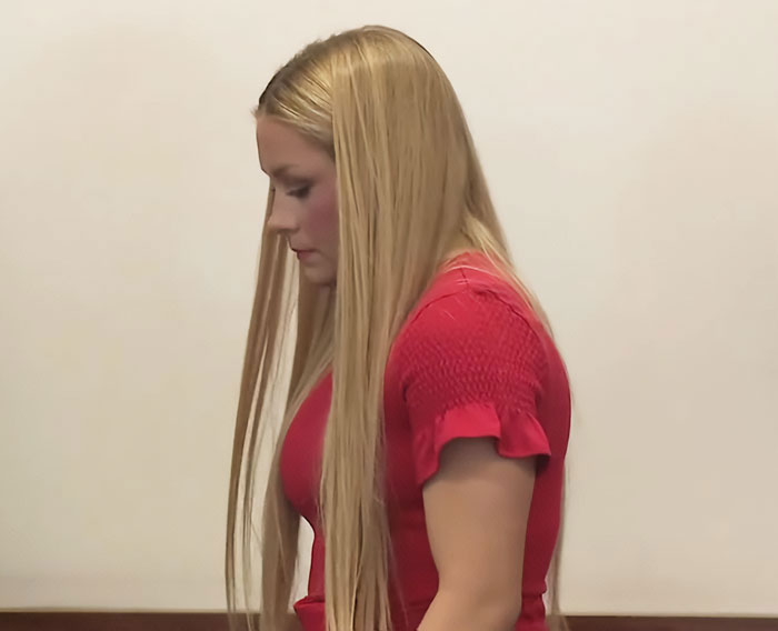 Young cheerleader with long blonde hair, wearing a red top, appearing solemn in an indoor setting related to the news event. Young cheerleader with long blonde hair, wearing a red top, appearing solemn in an indoor setting related to the news event.