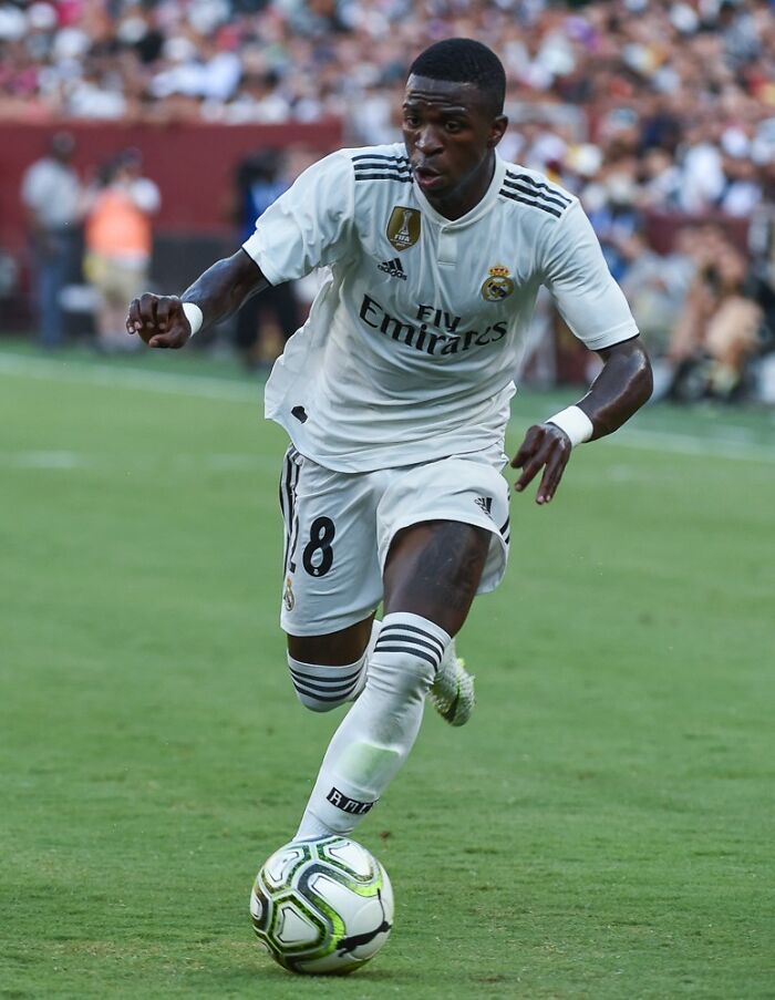 Soccer player in white Real Madrid uniform controlling the ball during a match of highest paid athletes 2025.