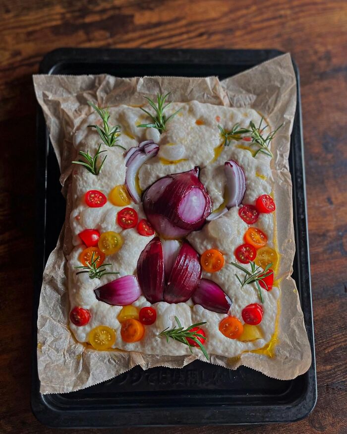 Creative meal by a Japanese mom featuring a spider design with red onion, black olives, cherry tomatoes, and rosemary on bread.