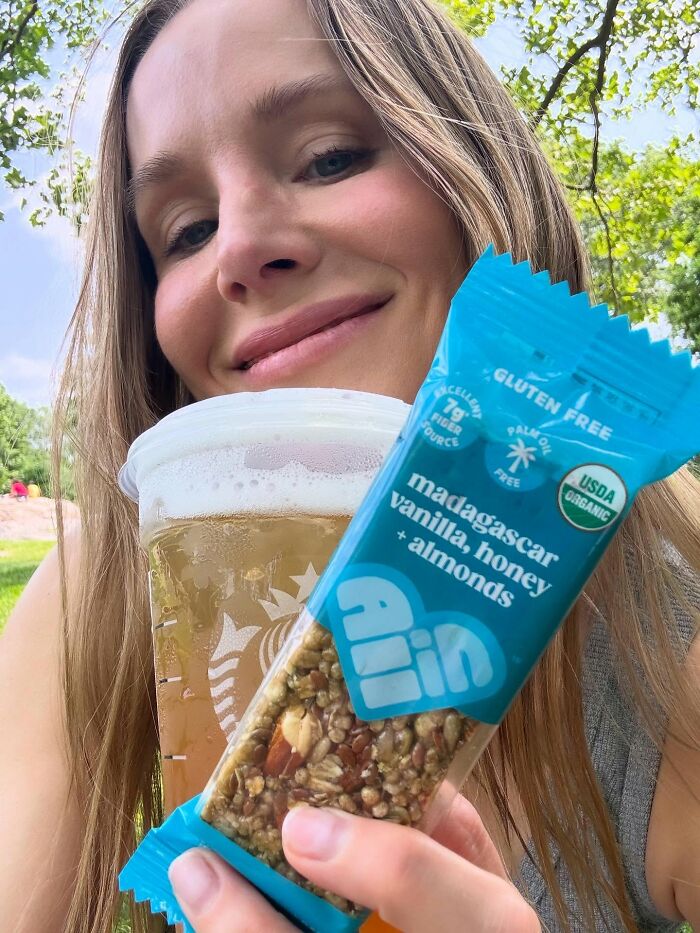 Woman holding a healthy snack bar and drink outdoors, illustrating a simple biohacking trick to stay fit. Woman holding a healthy snack bar and drink outdoors, illustrating a simple biohacking trick to stay fit.