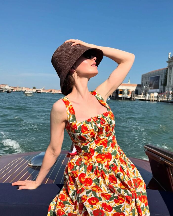 Lily Collins with a skinny appearance wearing a floral dress and brown hat, posing by the water on a sunny day. Lily Collins with a skinny appearance wearing a floral dress and brown hat, posing by the water on a sunny day.