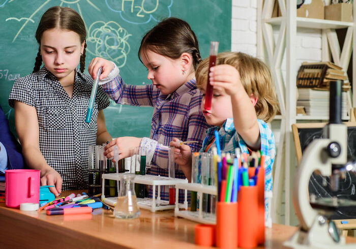 Three children conducting science experiments with test tubes in a classroom, illustrating shocking school incidents.