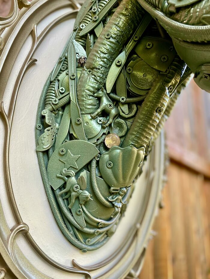 Recycled metal pieces crafted into a stunning animal sculpture mounted on a wooden fence outdoors.