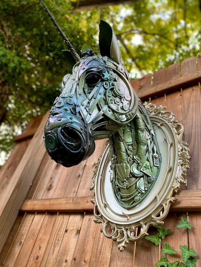 Recycled metal pieces crafted into a stunning animal sculpture mounted on a wooden fence outdoors.