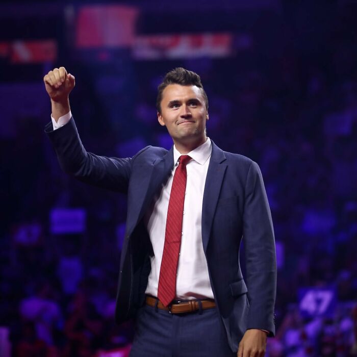Charlie Kirk in a suit and red tie raising his fist on stage, linked to predicted passing in eerie post years ago. Charlie Kirk in a suit and red tie raising his fist on stage, linked to predicted passing in eerie post years ago.