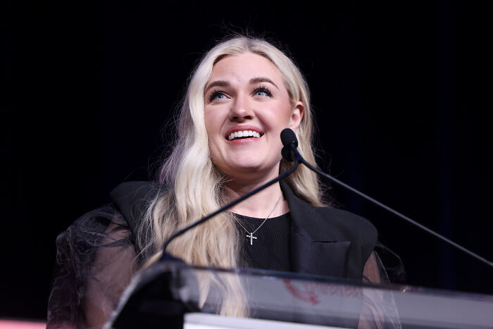 Erika Kirk speaking at a podium, smiling with long blonde hair, related to gesture during husband's funeral viral claim. Erika Kirk speaking at a podium, smiling with long blonde hair, related to gesture during husband's funeral viral claim.