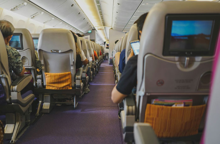 Passengers seated inside an airplane cabin during a flight, illustrating a passenger nightmare flight experience. Passengers seated inside an airplane cabin during a flight, illustrating a passenger nightmare flight experience.