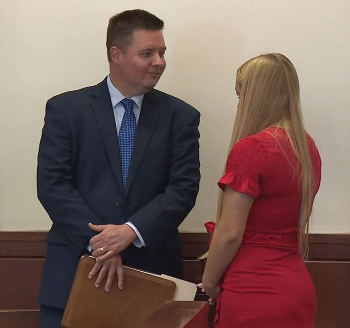 Cheerleader in a red dress appears glammed up in court speaking with a man in a navy blue suit and tie. Cheerleader in a red dress appears glammed up in court speaking with a man in a navy blue suit and tie.