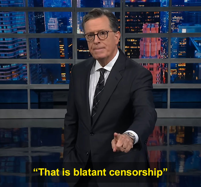 Stephen Colbert in a suit pointing, discussing censorship on a late-night talk show with cityscape studio background. Stephen Colbert in a suit pointing, discussing censorship on a late-night talk show with cityscape studio background.