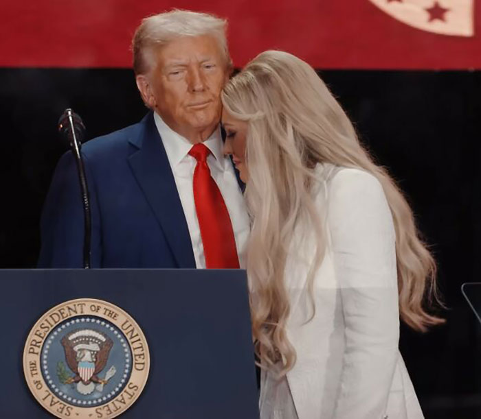 Woman with long blonde hair leaning close to man in blue suit and red tie at a podium with presidential seal during public event WWE level stuff controversy Woman with long blonde hair leaning close to man in blue suit and red tie at a podium with presidential seal during public event WWE level stuff controversy