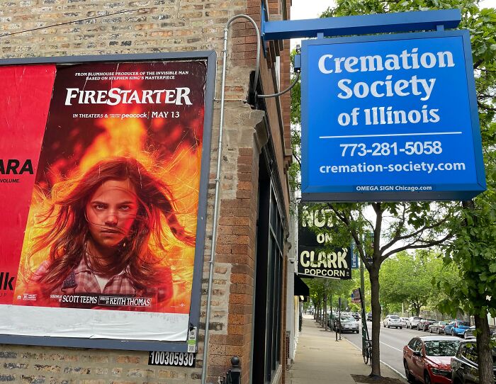 Billboard ad for fire-themed movie next to sign for Cremation Society, showing advertising placement fails that made people laugh.