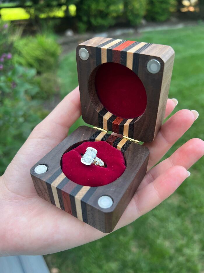 Handcrafted wooden ring box with red velvet interior holding an elegant diamond ring, showcasing cool handmade creations.