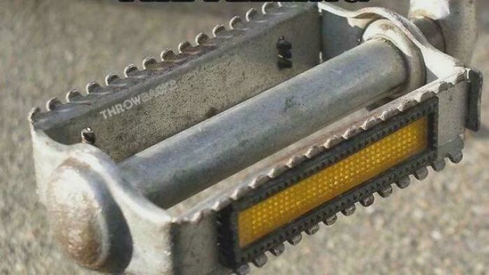 Old rusty bicycle pedal with yellow reflector and metal teeth, evoking nostalgia and making you feel old as heck.
