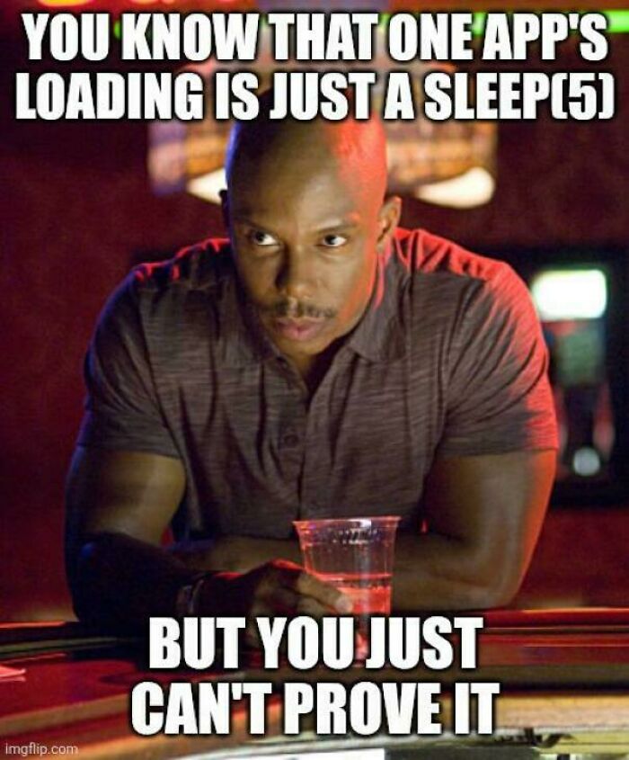 Man with serious expression holding a drink in a dim bar with a programming and computer science meme about app loading.