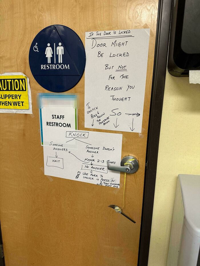 Restroom door with hilariously random signs and instructions including a fork to unlock, showcasing funny notes and messages.