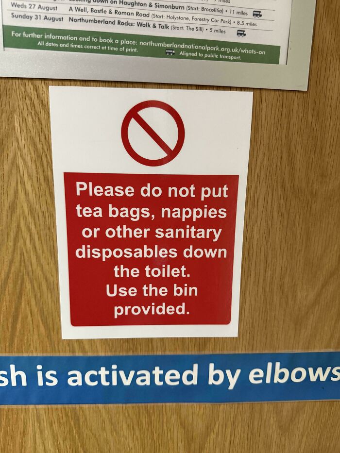 Sign on wooden door humorously reminding not to flush tea bags, nappies, or disposables, reflecting random notes and messages.