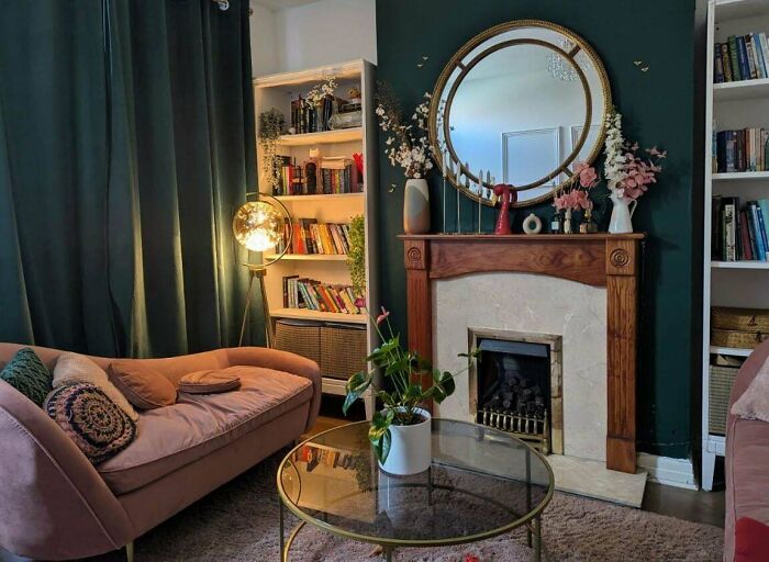 Cozy living room with stylish home decoration featuring a round mirror, bookshelf, and velvet sofa, showcasing proud home decor ideas.